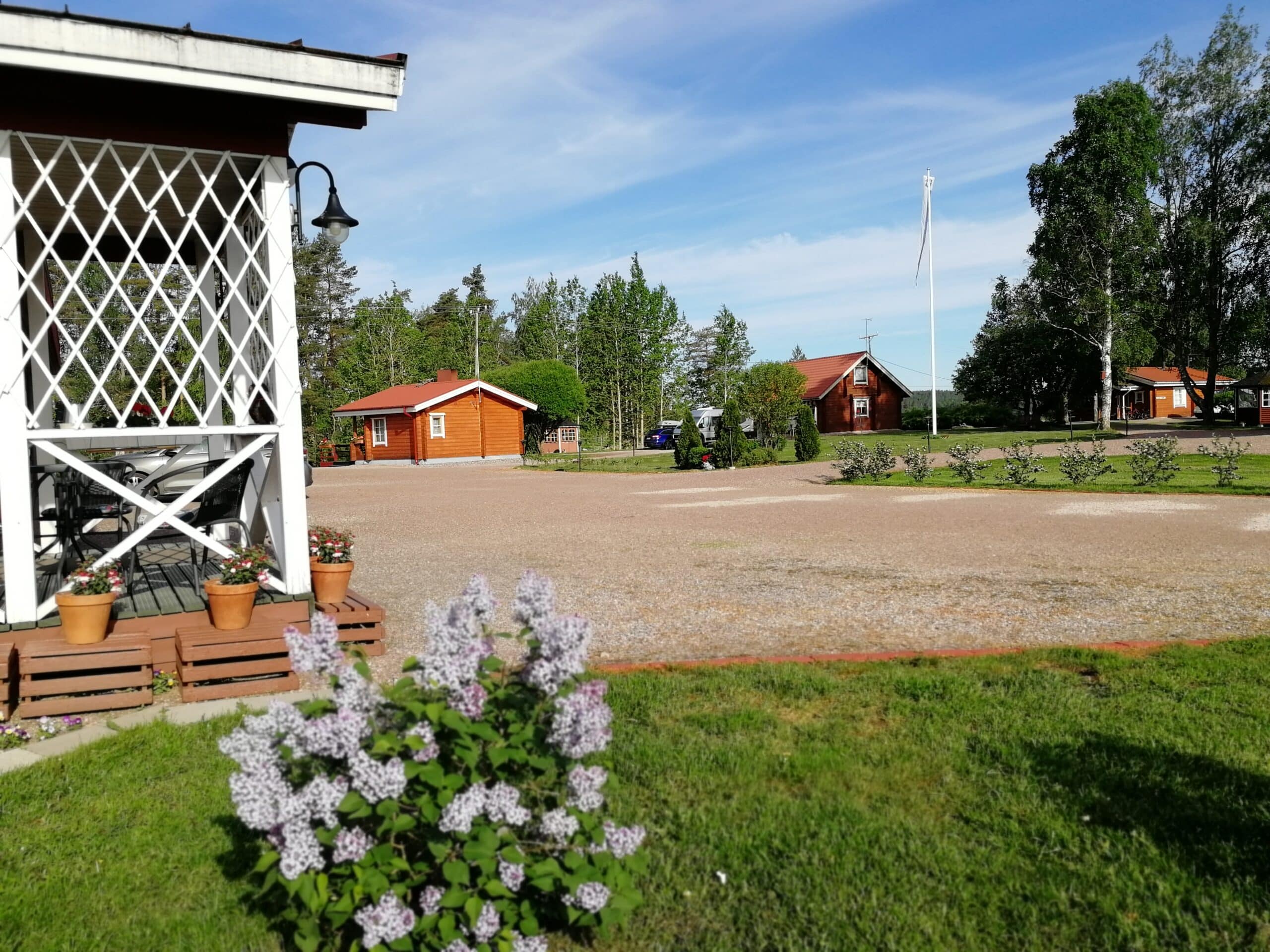 Silfvastas Holiday Homes . Etualalla lomahuoneisto Honeyn kuisti, josta avautuu näkymä mökkeihin ja piha-alueelle.